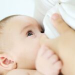 Newborn baby breastfeeding with support of breast milk increasing powder supplements