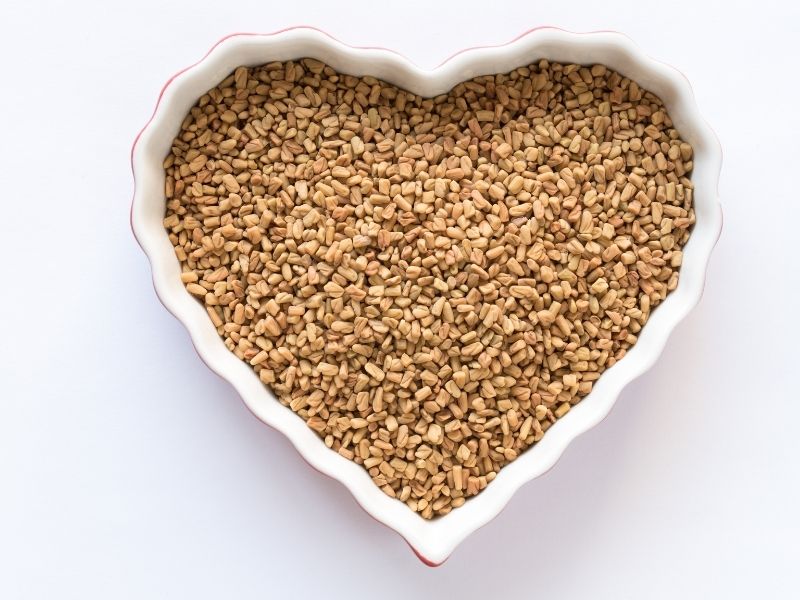 Heart-shaped bowl filled with fenugreek seeds, commonly used as a breast milk increasing powder in natural remedies