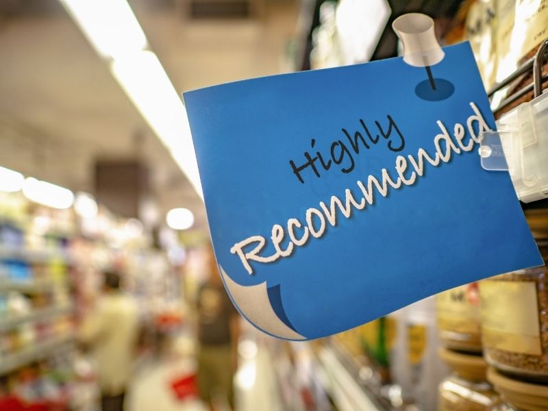 Blue sign with text ‘Highly Recommended’ in a grocery store aisle – representing our top recommended breast milk increasing powder for lactating mothers.