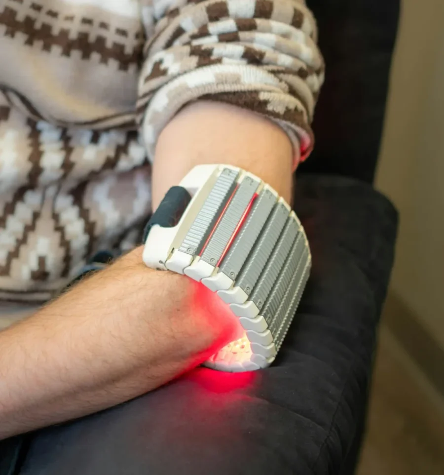 A person using red light therapy on their arm, a treatment method sometimes explored for joint pain relief caused by the Chikungunya virus