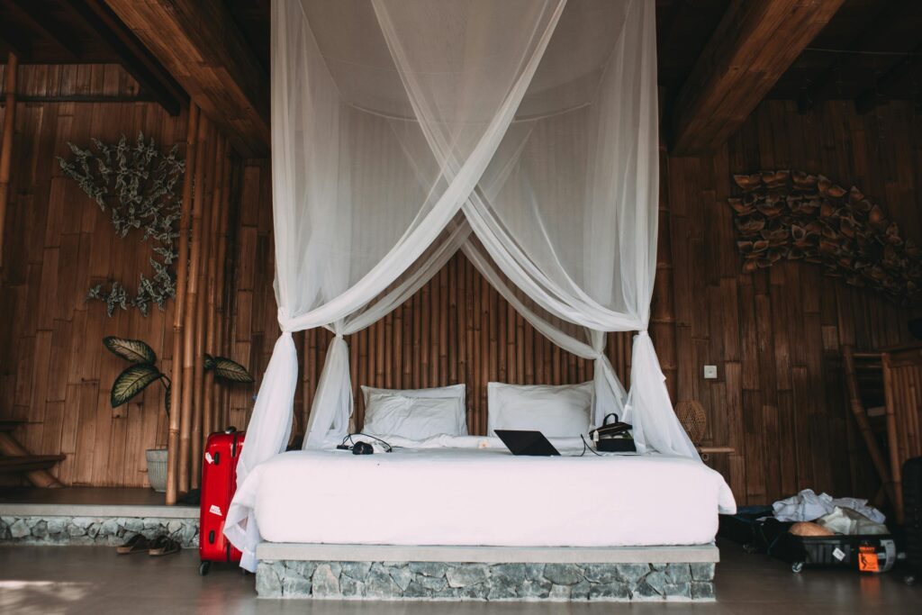 A bed with a white mosquito net in a wooden room, used for protection against mosquito bites and the spread of the Chikungunya virus.