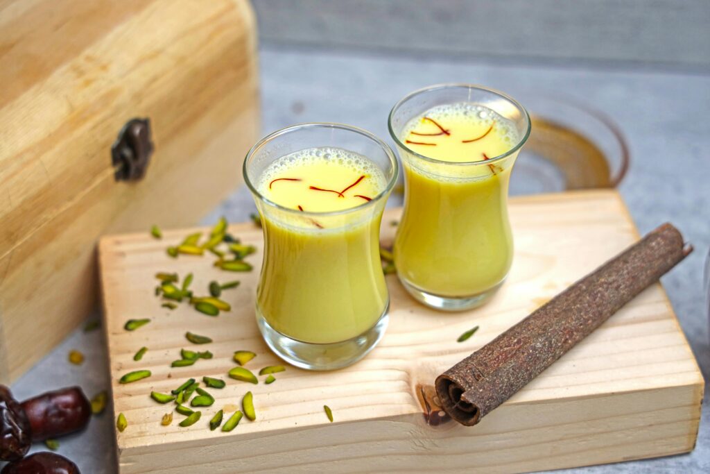 Two glasses of saffron milk with pistachios and cinnamon, a natural remedy often linked to boosting immunity against the Chikungunya virus.